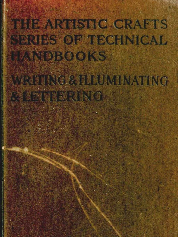A hand holding a broad nib pen writing elegant dark letters on cream paper beside an ink bottle and ruled practice sheets.